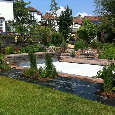a garden with a pool surrounded by lush green grass